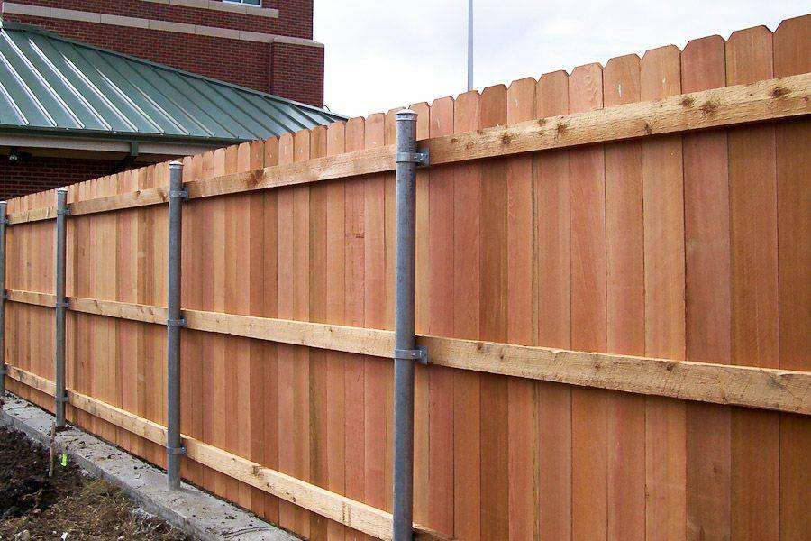 Деревянный забор на металлических столбах: особенности строительства